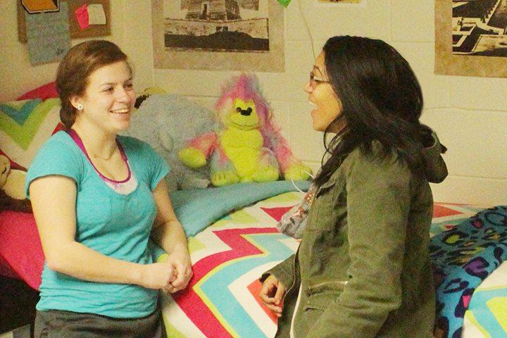 a resident assistant speaks to another student in a dorm room